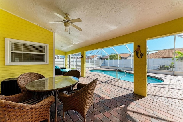 view of swimming pool with ceiling fan, glass enclosure, and a patio