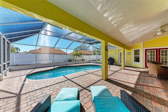 view of pool featuring ceiling fan, glass enclosure, and a patio area