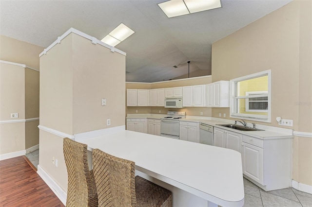 kitchen with white appliances, white cabinets, kitchen peninsula, and sink