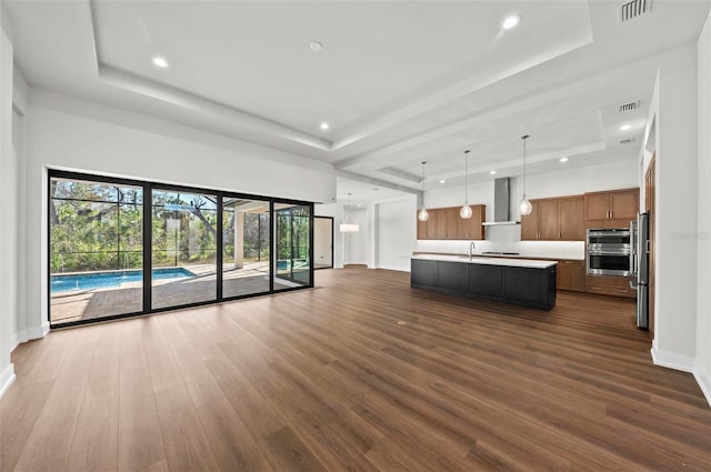 unfurnished living room featuring dark hardwood / wood-style floors, sink, and a tray ceiling