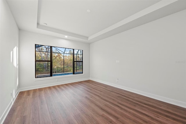 unfurnished room with hardwood / wood-style floors and a tray ceiling