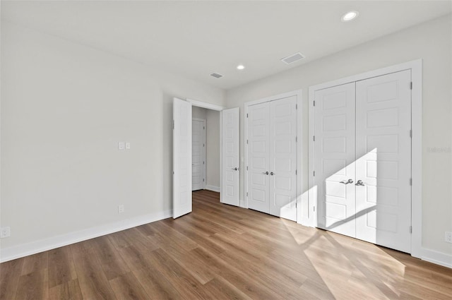 unfurnished bedroom with hardwood / wood-style flooring and two closets