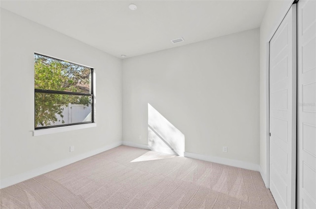 unfurnished bedroom featuring light colored carpet and a closet