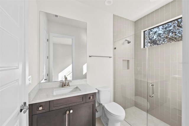 bathroom with toilet, vanity, and a shower with door