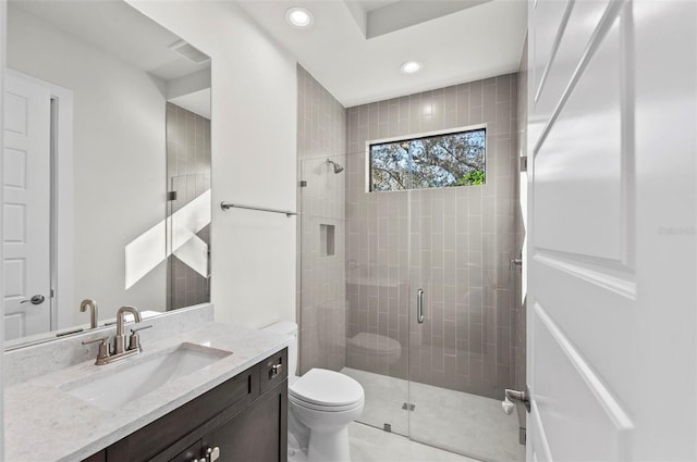 bathroom featuring toilet, a shower with shower door, and vanity