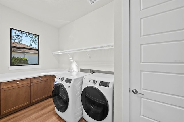 washroom with cabinets, sink, independent washer and dryer, and light hardwood / wood-style floors