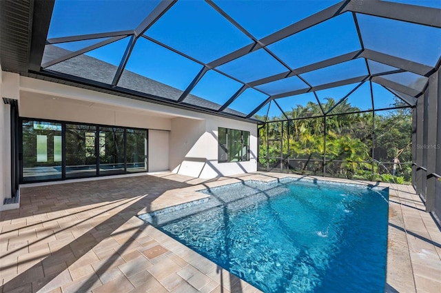 view of pool with glass enclosure and a patio