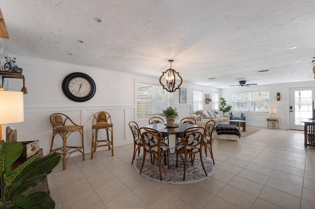 tiled dining room featuring ceiling fan with notable chandelier