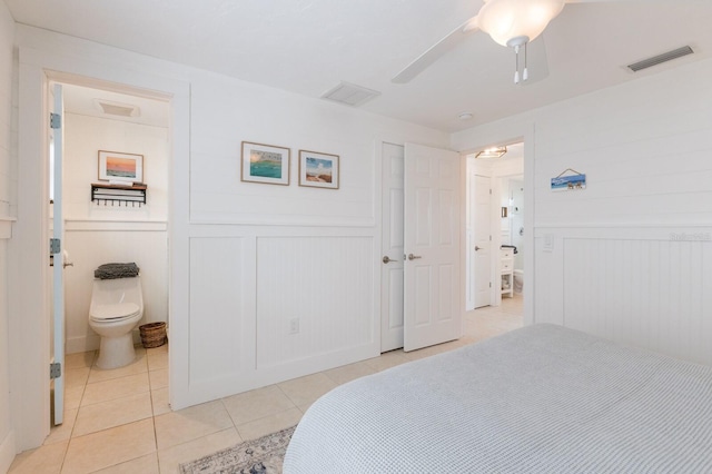 bedroom featuring ceiling fan, ensuite bath, and light tile patterned floors