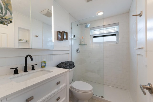 bathroom with vanity, tiled shower, and toilet