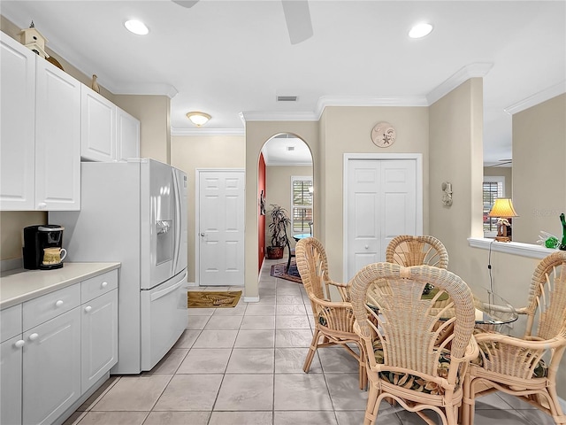 kitchen featuring light tile patterned floors, white cabinetry, white refrigerator with ice dispenser, and ornamental molding