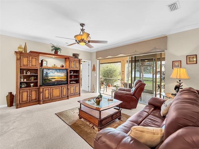 living room with ceiling fan, ornamental molding, and carpet flooring