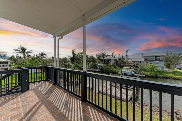 balcony at dusk featuring a water view