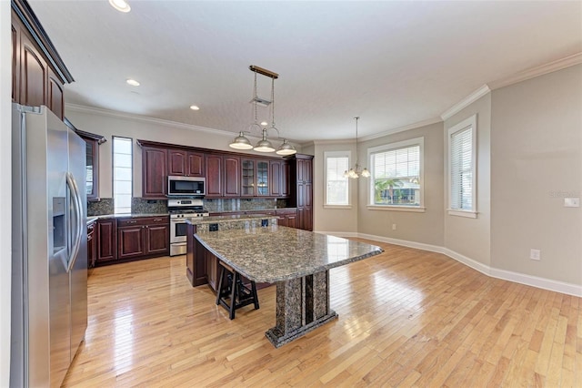 kitchen with appliances with stainless steel finishes, light hardwood / wood-style floors, a kitchen bar, decorative backsplash, and a kitchen island