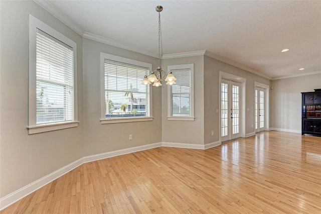 unfurnished dining area featuring an inviting chandelier, ornamental molding, and light hardwood / wood-style floors