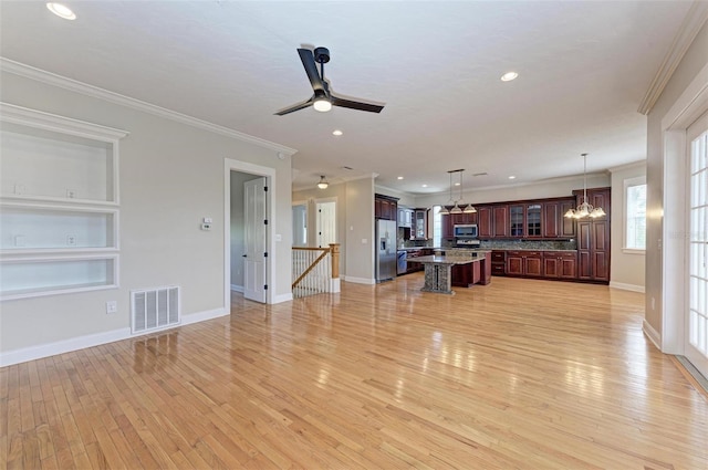 unfurnished living room featuring ceiling fan with notable chandelier, built in features, light hardwood / wood-style floors, and crown molding