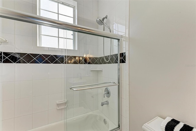 bathroom with toilet and bath / shower combo with glass door