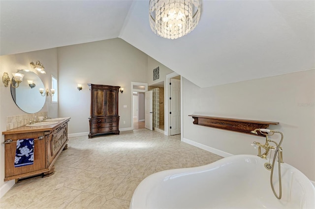 bathroom featuring a tub, a notable chandelier, vaulted ceiling, and vanity