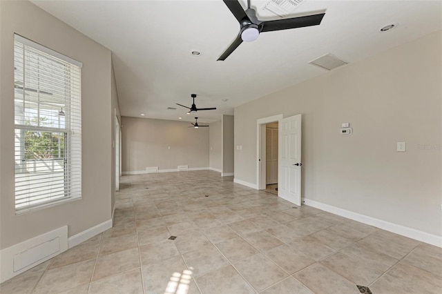 spare room featuring light tile patterned floors, visible vents, a ceiling fan, and baseboards