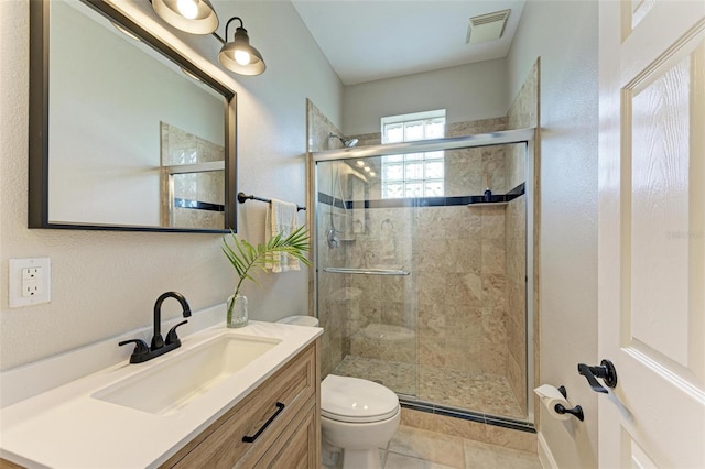 bathroom featuring toilet, vanity, visible vents, a shower stall, and tile patterned floors