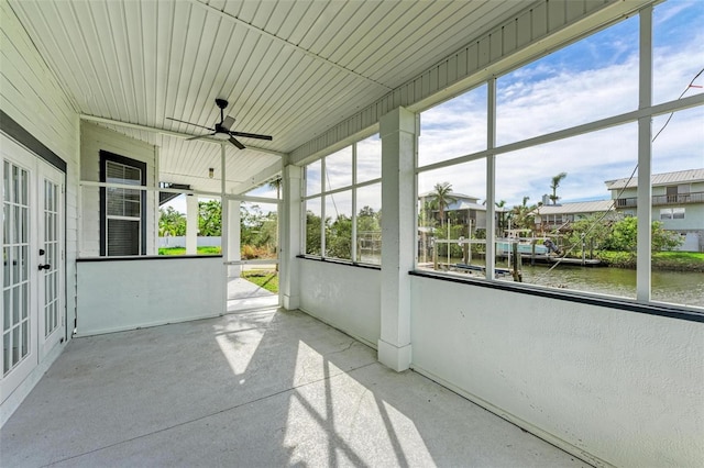 unfurnished sunroom featuring ceiling fan and a water view