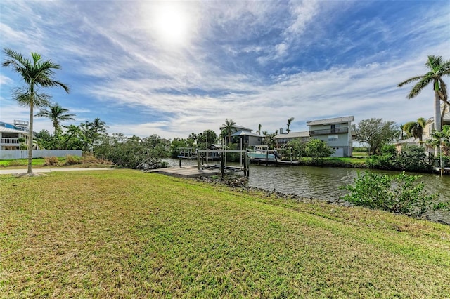 dock area featuring a water view, boat lift, and a yard