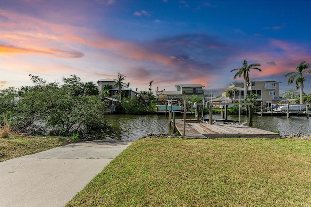 view of dock with a lawn, a water view, and boat lift