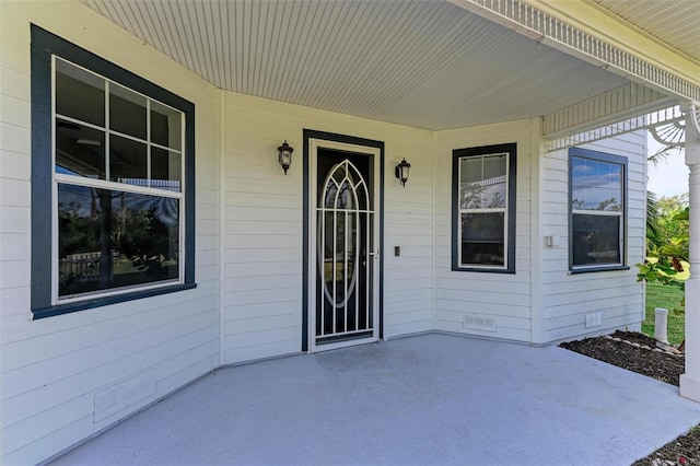 entrance to property featuring a patio, a porch, and crawl space