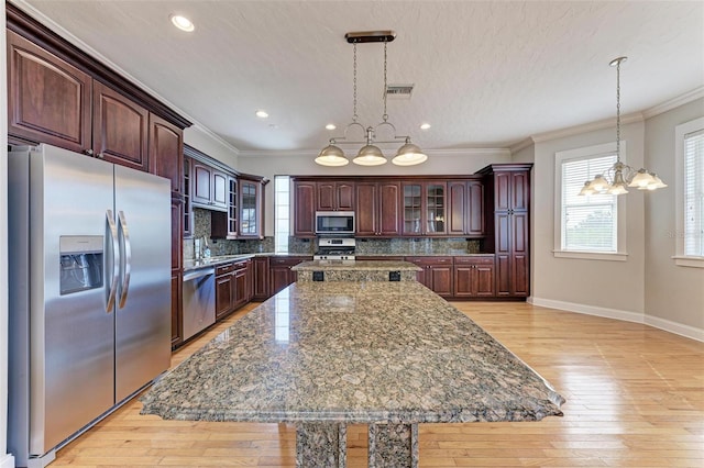 kitchen with stainless steel appliances, light wood-style floors, visible vents, and decorative backsplash