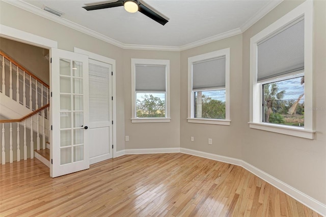 empty room featuring hardwood / wood-style flooring, baseboards, stairway, and ornamental molding