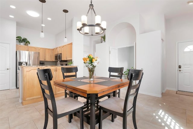 dining space featuring a towering ceiling, a chandelier, and light tile patterned floors