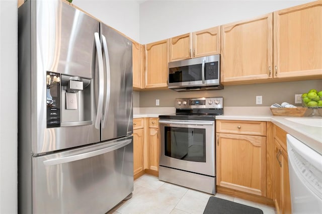 kitchen with stainless steel appliances, light tile patterned flooring, and light brown cabinetry