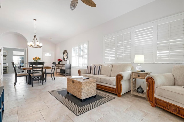 living room with ceiling fan with notable chandelier and vaulted ceiling