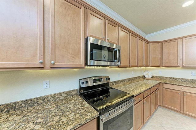 kitchen featuring a textured ceiling, light tile patterned floors, dark stone countertops, ornamental molding, and stainless steel appliances