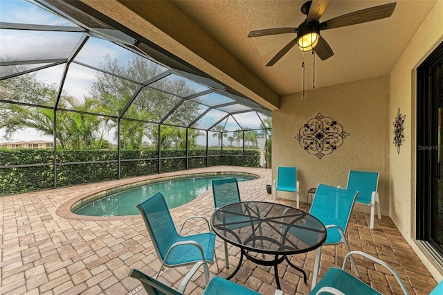 view of swimming pool featuring a patio area, ceiling fan, and glass enclosure