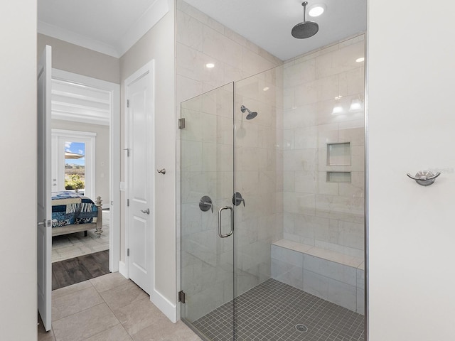 bathroom featuring tile patterned flooring, a shower with door, and ornamental molding