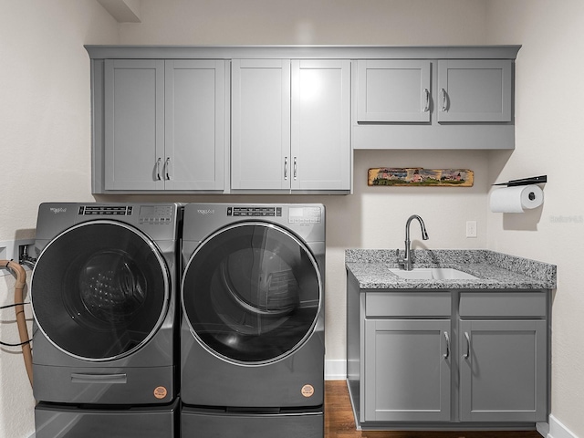 laundry area with washing machine and dryer, cabinets, and sink