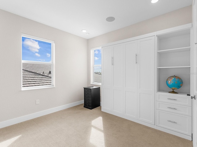 unfurnished bedroom featuring light carpet, a closet, and multiple windows