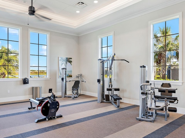 exercise room with ceiling fan, crown molding, and a tray ceiling