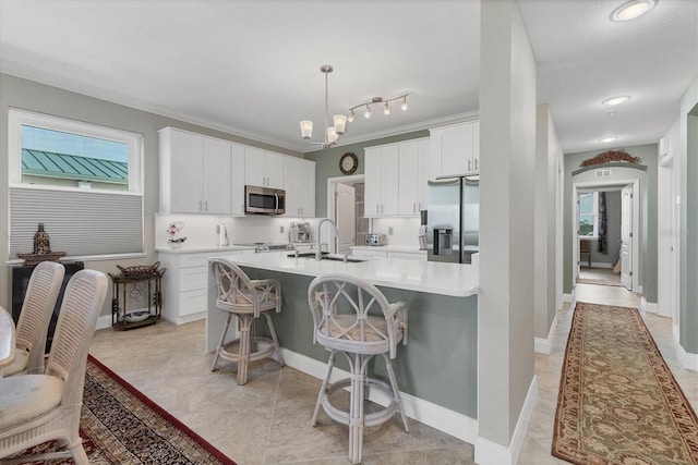 kitchen featuring pendant lighting, white cabinetry, a kitchen island with sink, a kitchen breakfast bar, and stainless steel appliances