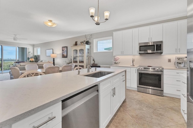 kitchen featuring hanging light fixtures, white cabinets, sink, and stainless steel appliances