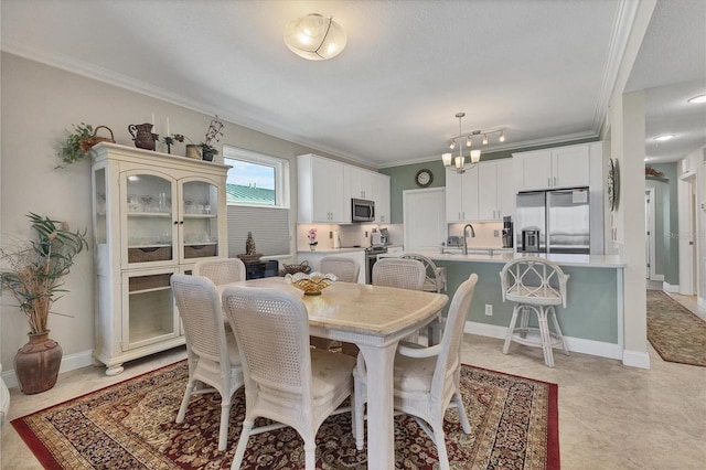 dining room featuring sink, crown molding, and a notable chandelier