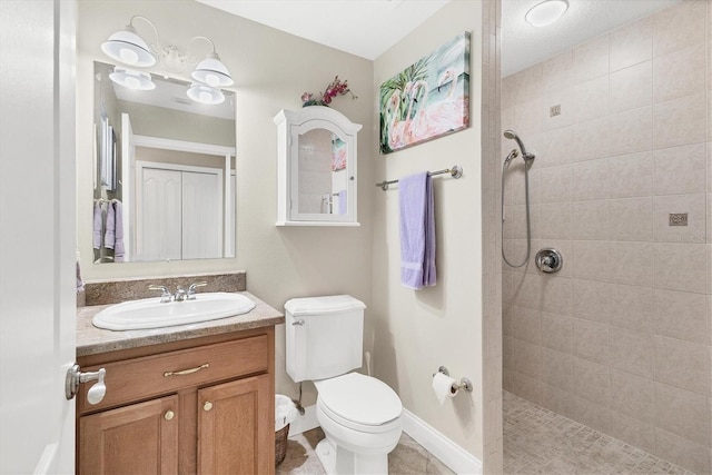 bathroom with toilet, vanity, and tiled shower