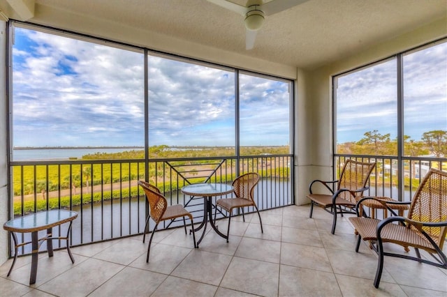 sunroom featuring ceiling fan and a water view