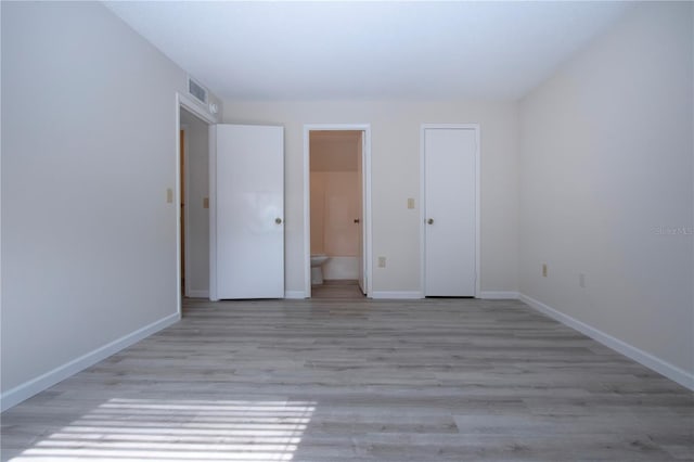 unfurnished bedroom featuring light hardwood / wood-style floors and connected bathroom