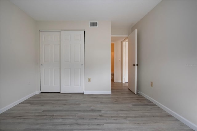 unfurnished bedroom with a closet and light wood-type flooring