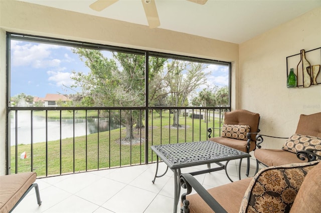 sunroom featuring ceiling fan and a water view