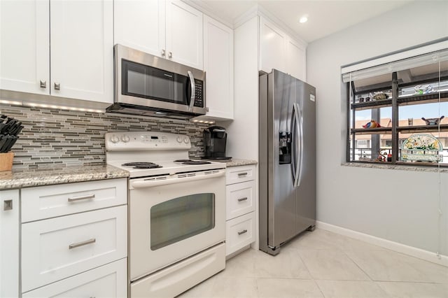 kitchen with light tile patterned floors, appliances with stainless steel finishes, white cabinetry, tasteful backsplash, and light stone countertops