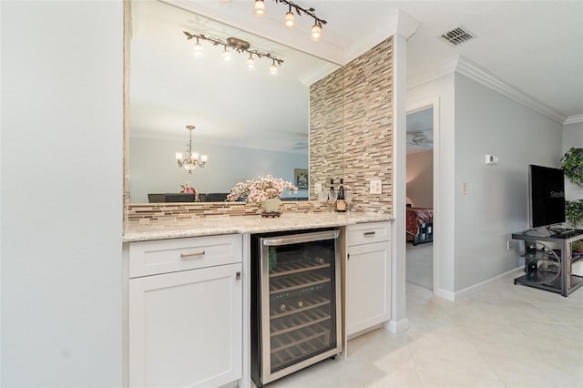 bar with white cabinetry, wine cooler, decorative backsplash, ornamental molding, and light stone counters