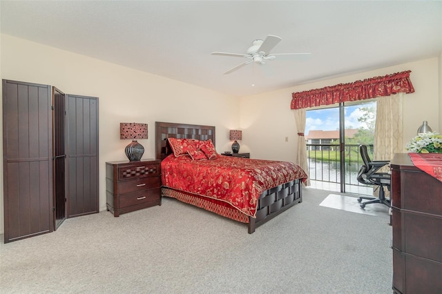 carpeted bedroom with access to exterior, ceiling fan, and a water view